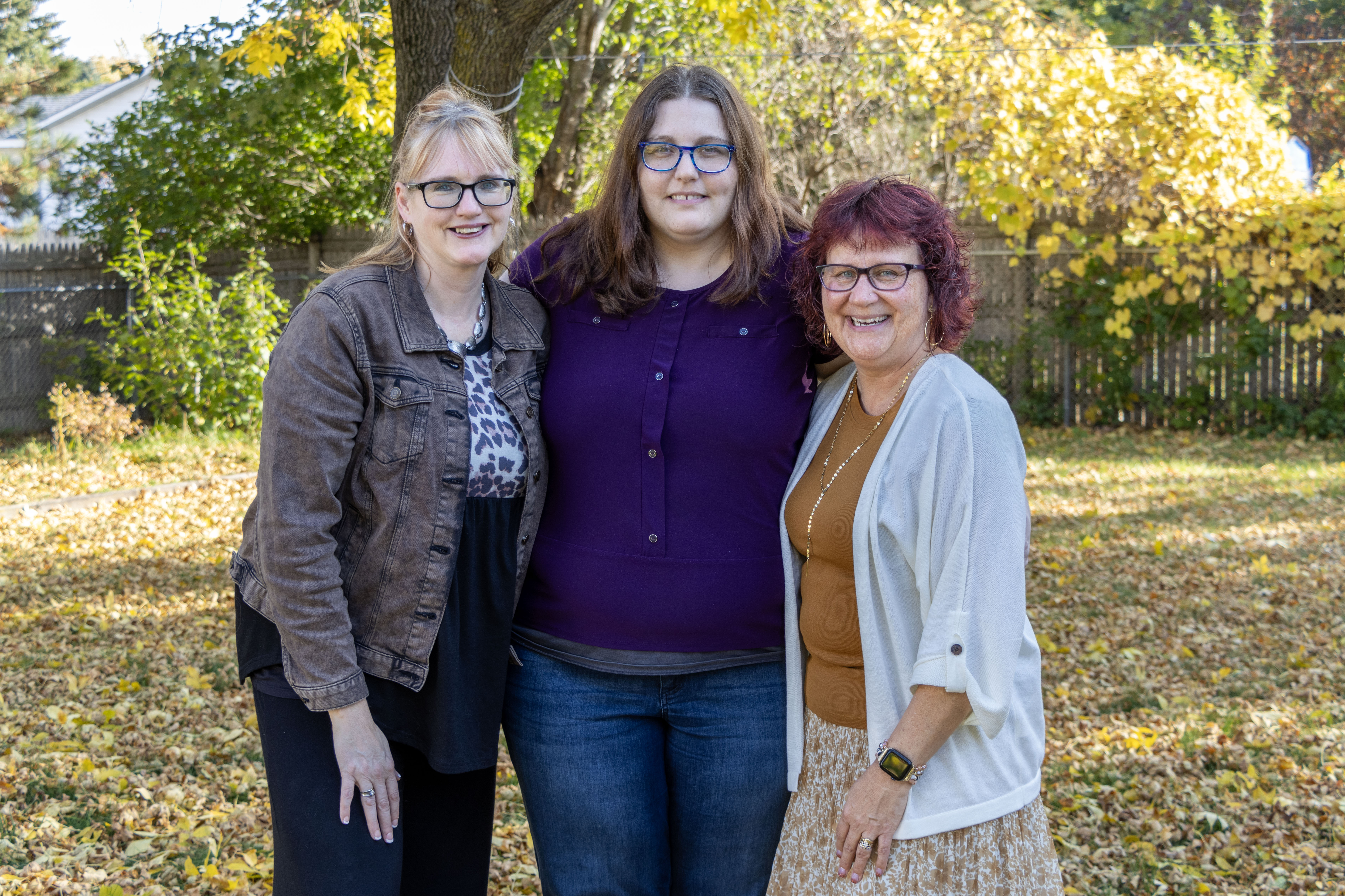 three women standing together outside smiling at the camera