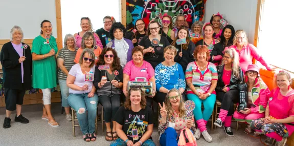 a diverse group of women in bright apparel posing for a photo