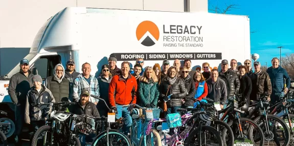 a large group of people posing outside in front of a van surrounded by bikes