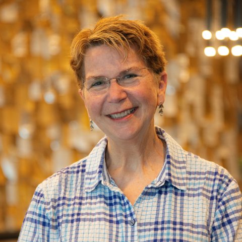 A woman smiling in front of a golden backdrop 