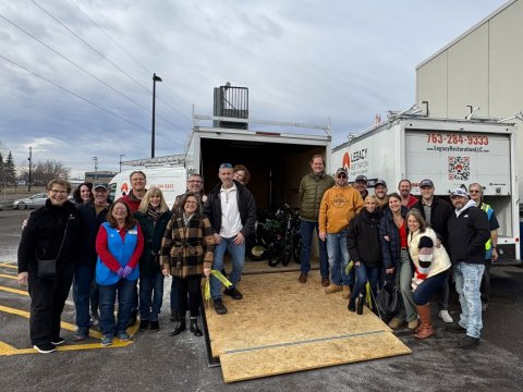 A group of people standing in front of a trailer filled with bicycles smiling in an outdoor setting