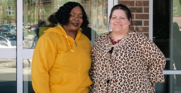 Two women standing outside a building smiling