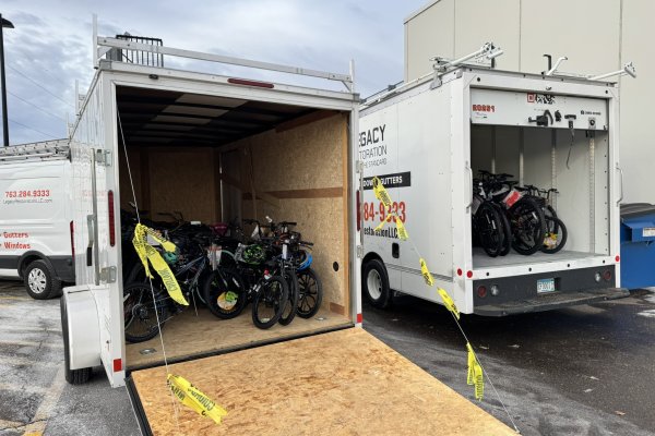 two trailers parked outside full of bicycles of different sizes and colors 